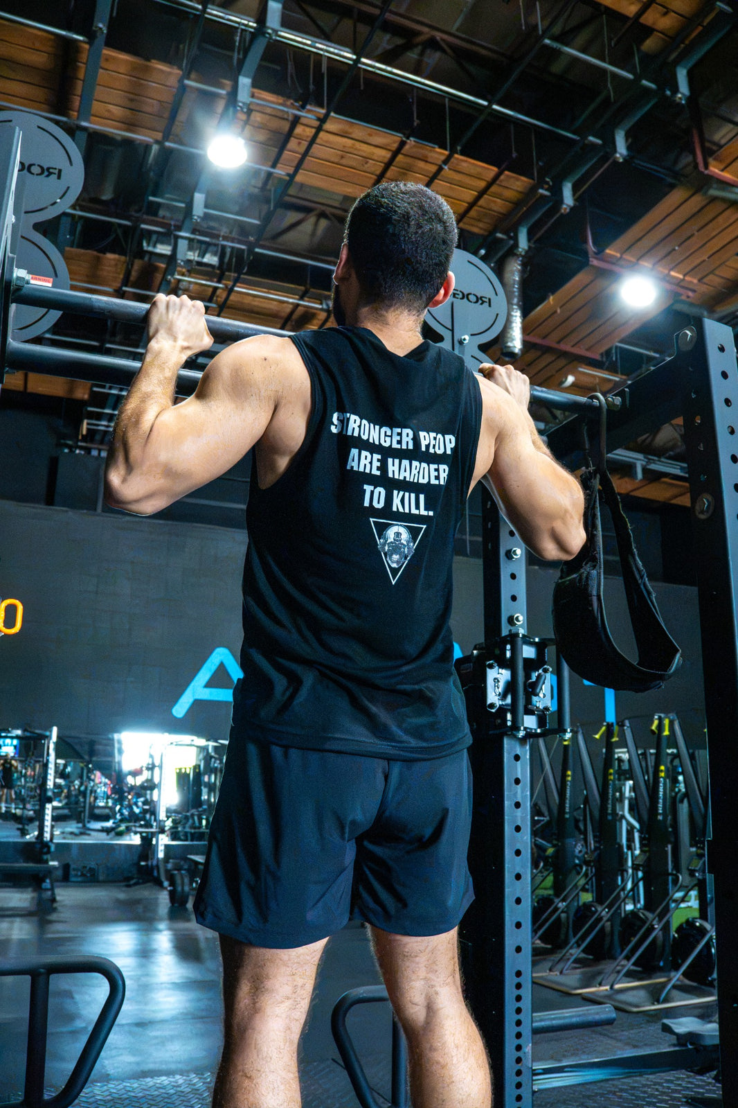 Athlete wearing The Razor muscle tank during pull-ups, showing the back graphic