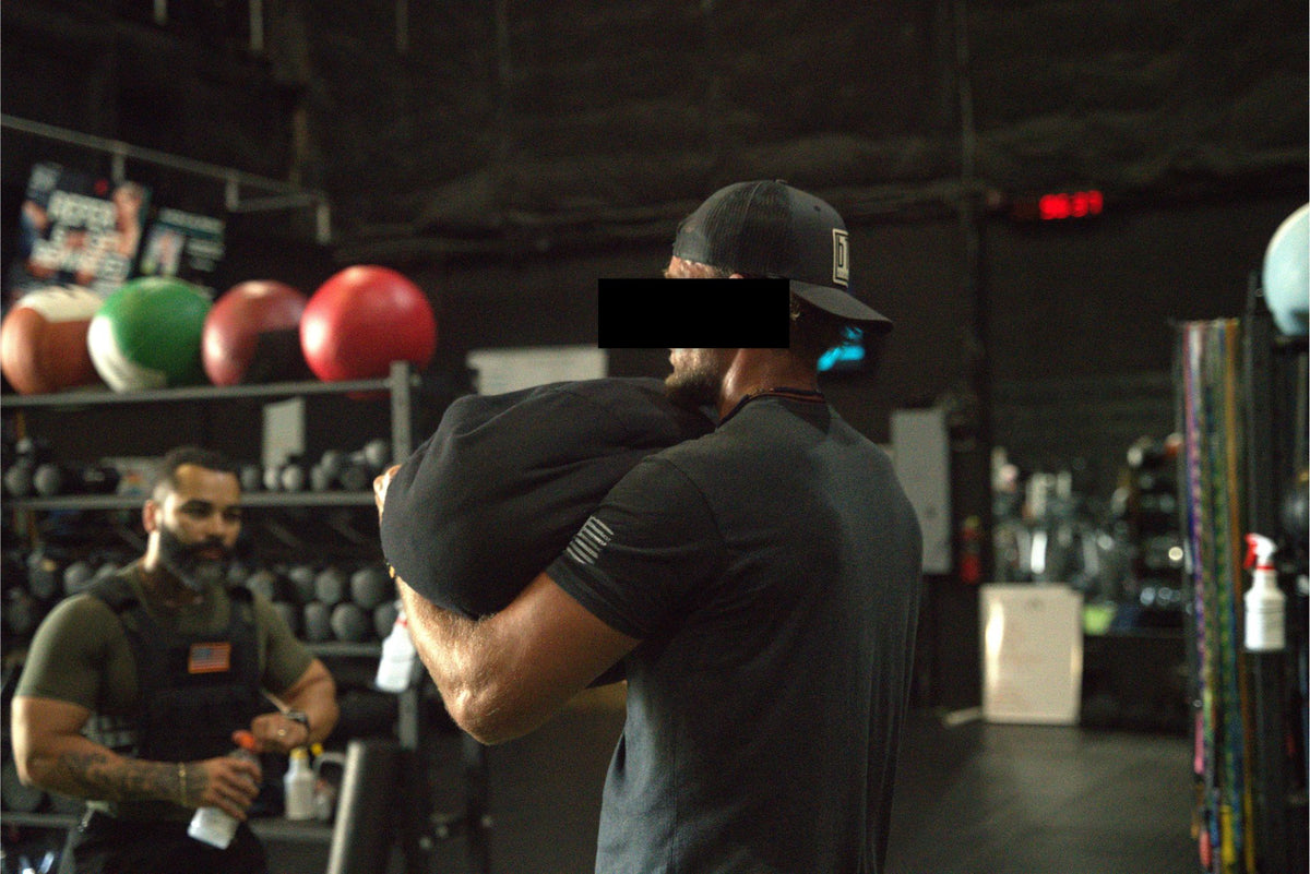 Athlete carrying a heavy sandbag during a gym training session